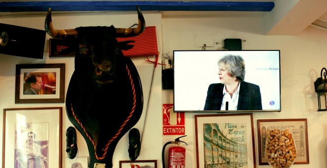 La primera ministra Británica retransmitida por la televisión de un bar junto a la imagen de un toro.REUTERS/Jon Nazca