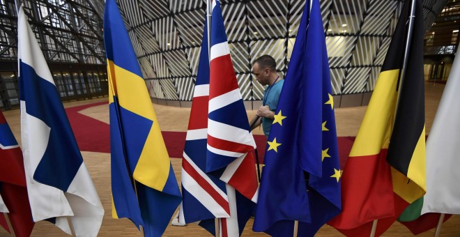 Un empleado limpia junto a las banderas europeas, dispuestas para la última cumbre de los lideres de la UE, en Bruselas, el pasado 9 de marzo. REUTERS/Dylan Martinez