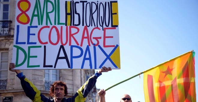 Un hombre sostiene una pancarta con la frase, en francés, '8 de abril histórico. El valor de la paz', junto a otro hombre con las banderas vasca y catalana, en baiona. REUTERS / Vincent West