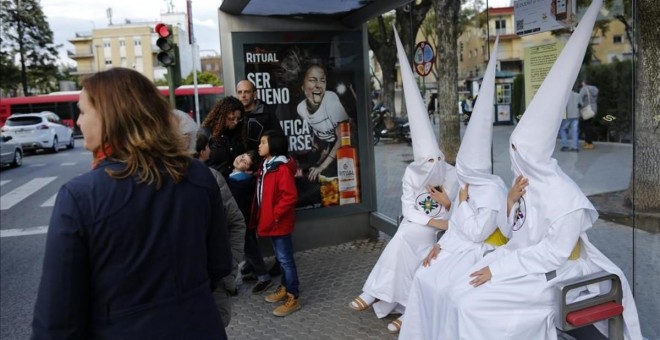 Unos nazarenos descansan en una parada de autobús en Sevilla. REUTERS/Marcelo del Pozo