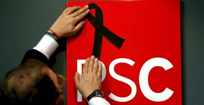 Un militante coloca un crespón negro en el logo del PSC de la sede en Barcelona tras conocerse el repentino fallecimiento de la socialista Carme Chacón hoy en Madrid. EFE/Toni Albir