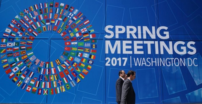Unos peatones pasan por delante del mural que anuncia la reunión de primavera del FMI y del Banco Mundial en Washington. AFP/Mandel Ngan
