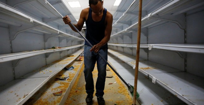 Un trabajador limpia las estanterías en un supermercado después de haber sido saqueado en Caracas. REUTERS / Carlos Garcia Rawlins