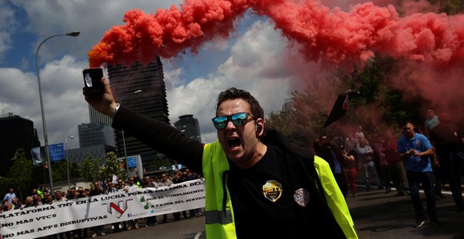 Un conductor de taxi sostiene una bengala durante la protesta contra las empresas de economía colaborativa como Uber, a las que acusan de 'dumping', este miércoles en Madrid. REUTERS/Susana Vera