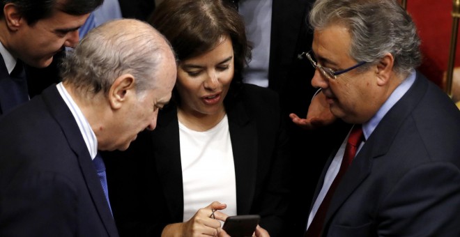 La vicepresidenta del Gobierno, Sorya Sáenz de Santamaría, conversa con el ministro del Interior, Juan Ignacio Zoido (d), y los diputados del PP Jorge Fernández Díaz (i) y José Luis Ayllón (2-i), durante un receso en el debate de las enmiendas a la totali