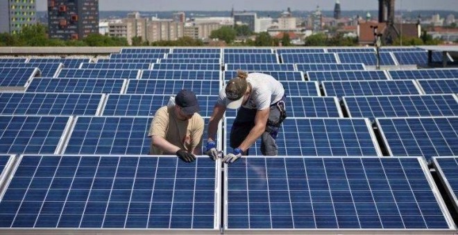Dos operarios trabajan en las placas solares situadas en la azotea de un edificio. EFE