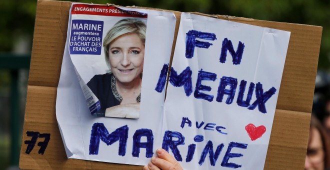 Un seguidor del Frente Nacional, sujeta una pancarta con la imagen de Marine Le Pen. REUTERS/Pascal Rossignol