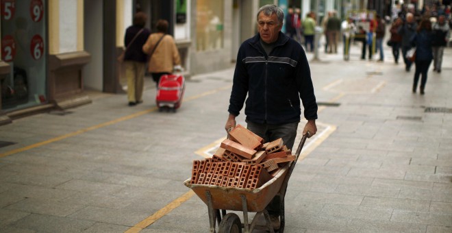 Un trabajador empuja una carretilla con ladrillos. REUTERS