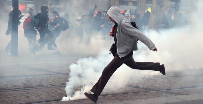 Un manifestante trata de alejar un bote de gas lacrimógeno en Nantes.- AFP