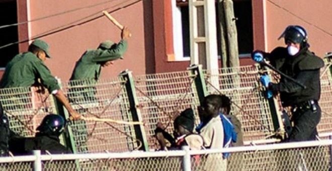 Agentes de la Guardia Civil y las fuerzas auxiliares marroquíes tratan de impedir que que varias personas migrantes salten la valla de Melilla.- CAMINANDO FRONTERAS