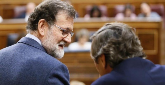 El presidente del Gobierno, Mariano Rajoy (i), conversa hoy con el portavoz del Partido Popular en el Congreso de los Diputados, Rafael Hernando, durante el pleno de hoy en la Cámara Baja, en el que se ha aprobado el real decreto ley de reforma de la esti