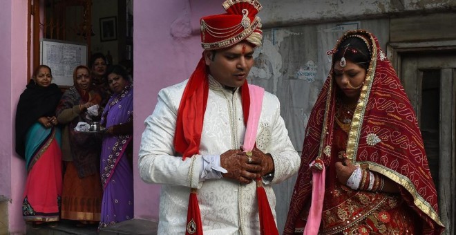 Una pareja de recién casados son observados por varios familiares tras visitar un templo en Nueva Delhi. AFP/ Prakash Singh