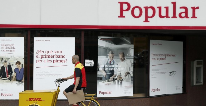 Un repartidor pasa ante una oficina del Banco Popular en Barcelona. EFE/Andreu Dalmau