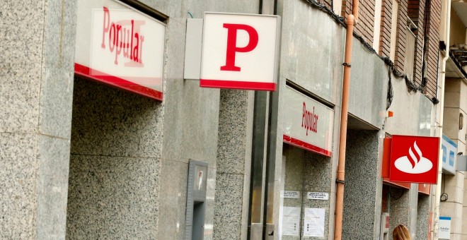 Una mujer usa un cajero automático en una oficina del Banco Santander junto a una sucursal del Banco Popular. REUTERS/Albert Gea