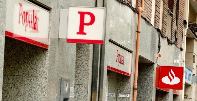 Una mujer usa un cajero automático en una oficina del Banco Santander junto a una sucursal del Banco Popular. REUTERS/Albert Gea