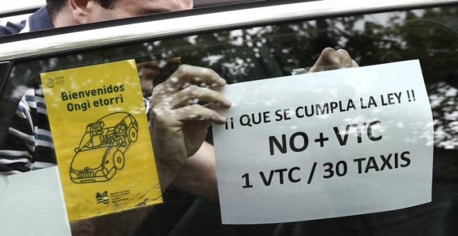 Un taxista pega en su taxi un cartel de protesta contra el incumplimiento de la proporción 1/30 entre licencias VTC y taxi. EFE