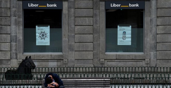 Un hombre sentado frente a la sede de Liberbank en Oviedo. REUTERS/Eloy Alonso