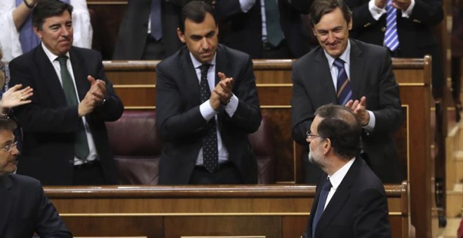 El presidente del Gobierno, Mariano Rajoy (d, abajo), es aplaudido por la bancada popular tras la votación en el pleno del Congreso de los Diputados. /EFE