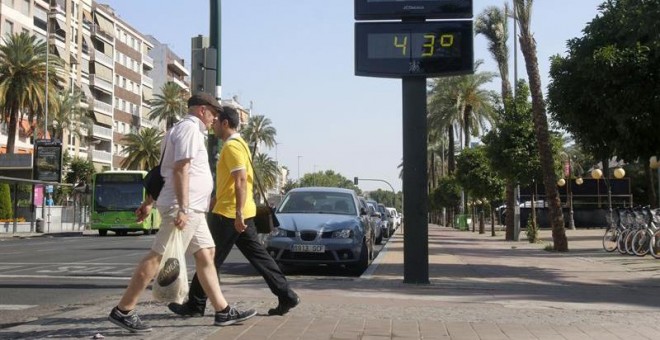 Dos personas pasan junto a un termómetro en Córdoba. - EFE