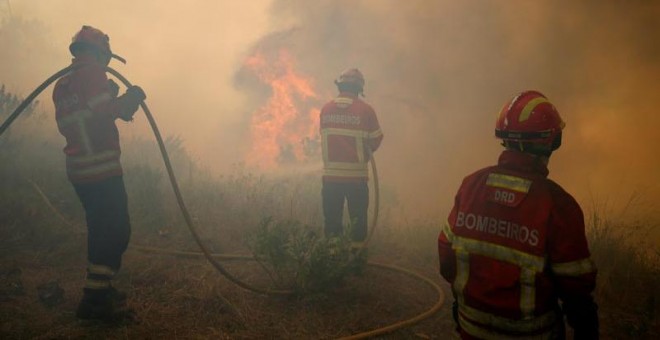 Tres bomberos trabajan para apagar las llamas en el bosque de Capelo, cerca de Gois. | RAFAEL MARCHANTE (EFE)