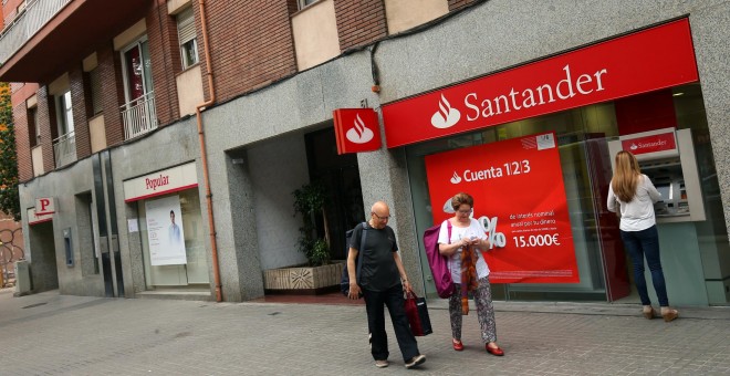 Una mujer utiliza el cajero automático de una oficina del Banco Santander, ubicado junto a un sucursal del Banco Popular, en Barcelona. REUTERS/Albert Gea