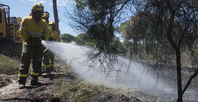 Efectivos del Infoca realizan labores de refresco tras el incendio forestal declarado el pasado sábado en el paraje 'La Peñuela' de Moguer (Huelva), que ha afectado a una amplia superficie de masa forestal del entorno de Doñana e incluso parte del parque