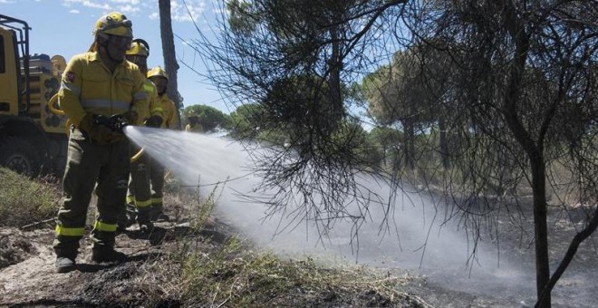 Efectivos del Infoca realizan labores de refresco tras el incendio forestal declarado el pasado sábado en el paraje 'La Peñuela' de Moguer (Huelva), que ha afectado a una amplia superficie de masa forestal del entorno de Doñana e incluso parte del parque