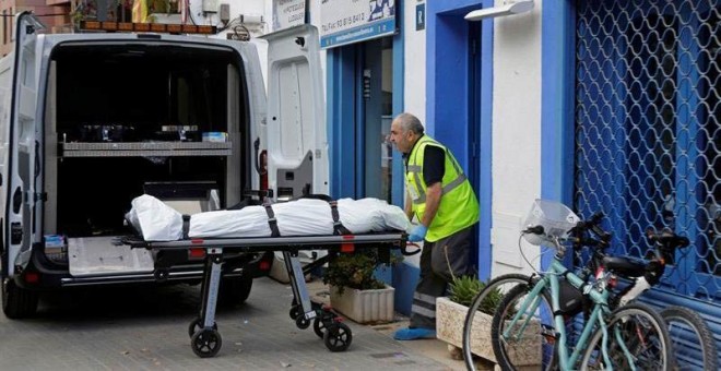 Un empleado de una funeraria saca el cadáver del hombre que ha fallecido al ser tiroteado cuando se encontraba en el bar de Vilanova i la Geltrú (Barcelona) donde trabajaba. | SUSSANA SÁEZ (EFE)