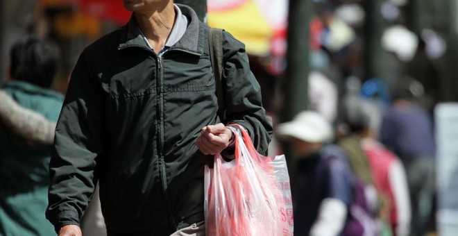 Un hombre carga una bolsa de plástico con la compra. AFP