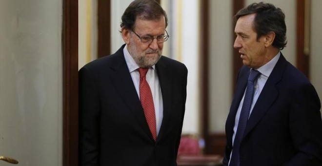 El presidente del Gobierno, Mariano Rajoy (i), conversa con el portavoz del PP en el Congreso, Rafael Hernando, en los pasillos de la Cámara Baja. /EFE