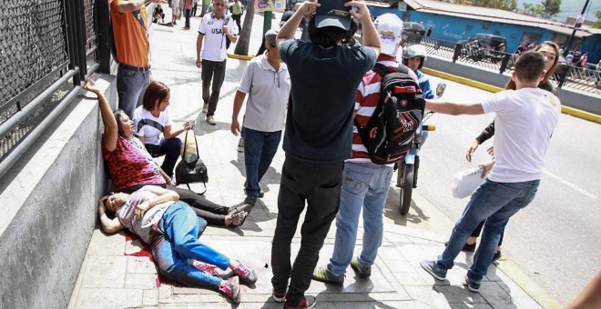 os mujeres yacen en el suelo durante un enfrentamiento entre un grupo de personas adeptas al oficialismo y personas opositoras al gobierno nacional durante la consulta popular hoy, domingo 16 de julio de 2017, en el oeste de Caracas (Venezuela). Dos perso