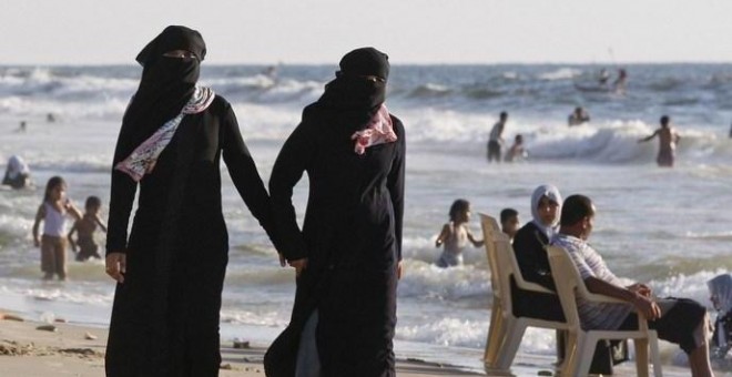 Dos mujeres con velo islámico en una playa.