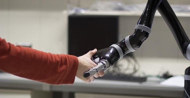 Un brazo humano y un brazo robótico se dan la mano./ WYSS CENTER
