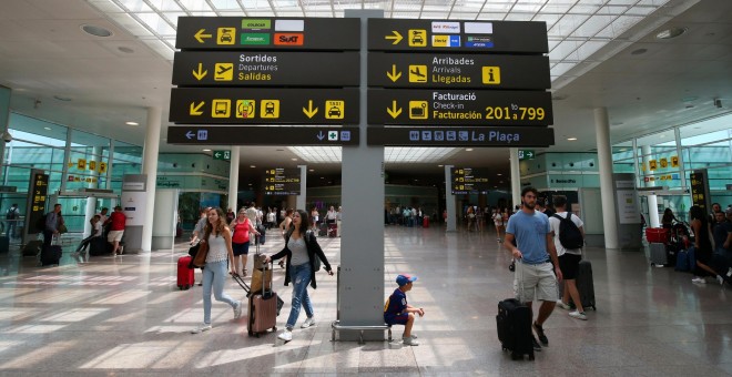 Viajeros junto a uno de los paneles informativos del Aeropuerto Barcelona-El Prat. REUTERS/Albert Gea