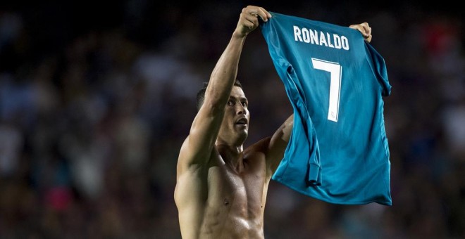 El jugador del Real Madrid Cristiano Ronaldo muestra su camiseta a los aficionados del Nou Camp, tras marcar el 1-2 de la ida de la Supercopa, lo que le valió la primera tarjeta amarilla. STRINGER / AFP