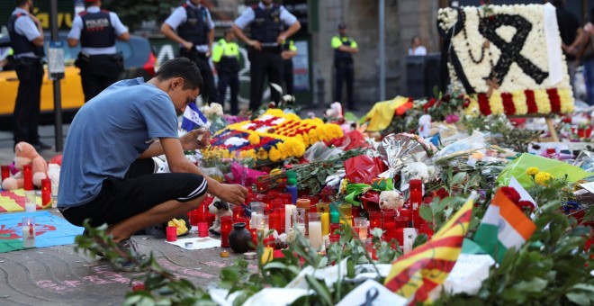 Un hombre enciende una vela en el memorial instalado en Las Ramblas, en memoria de las víctimas del atentado del pasado jueves. REUTERS/Susana Vera