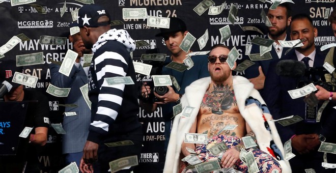 Mayweather arroja un fajo de billetes a la cara de McGregor durante uno de los careos para la promoción del combate.REUTERS/Noah K.Murray