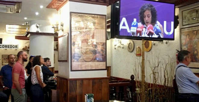 La secretaria general de Podemos Euskadi, Nagua Alba (3i), sigue en un bar cercano a la sede del partido en Vitoria las noticias sobre su anuncio de no presentarse a la reelección en las primarias que se celebrarán próximamente. EFE/David Aguilar