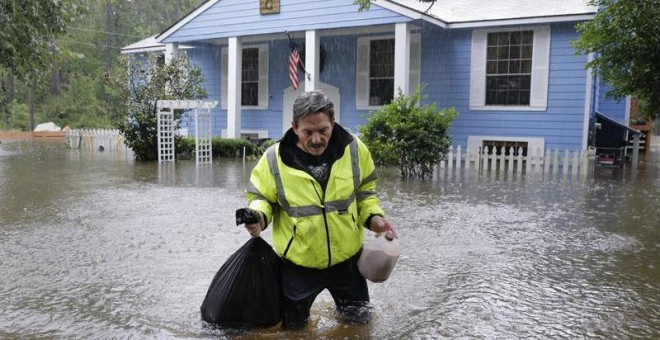 Doug Glassel camina por el agua mientras sujeta una bolsa de alimentos recuperados de su casa inundada en Spring, en el estado de Texas, en Estados Unidos. EFE
