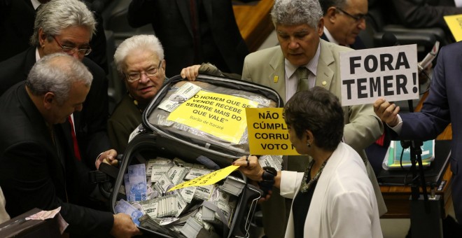 Diputados de la oposición en la cámara baja del Congreso brasileño levatan una maleta con dinero falso antes de la votación en la que se rechazó que el Tribunal Supremo juzgue al presidente Temer por corrupción /REUTERS (Adriano Machado)