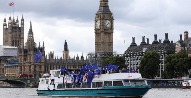 Un grupo de opopsitores al Brexit, con banderas de la UE en una barcaza por el Támesis de Londres, frente al edificio del Parlamento y la torre del 'Big Ben'. REUTERS/Luke MacGregor