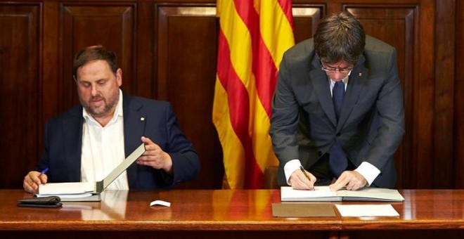 El presidente de la Generalitat, Carles Puigdemont, acompañado por el vicepresidente Oriol Junqueras, firma la convocatoria de referéndum. - EFE