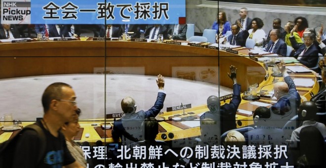 Peatones caminan en Tokio frente a una enorme pantalla que muestra un programa de noticias de televisión que informa sobre la sesión del Consejo de Seguridad de la ONU en Nueva York que acordó sanciones contra Corea del Norte. EFE/KIMIMASA MAYAMA