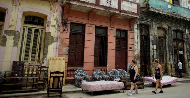 Turistas pasan al lado de muebles puestos a secar en la calle tras las inundaciones provocadas por el huracán Irma en La Habana /REUTERS (Alexandre Meneghini)