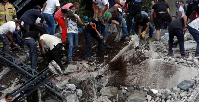 Varias personas buscan supervivientes entre los escombros de un edificio caído tras el terremoto en Ciudad de México. - REUTERS
