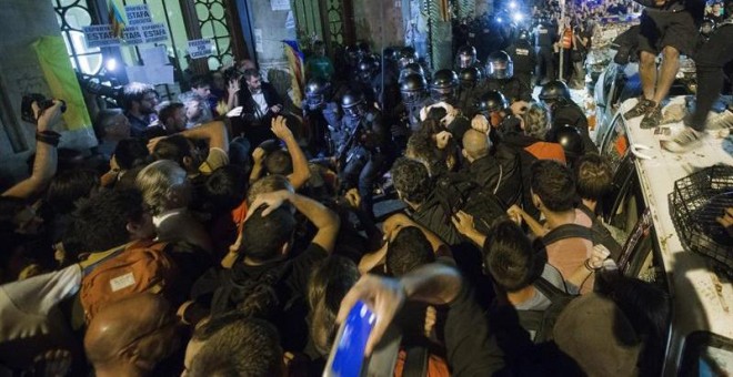 La Guardia Civil sale de la Conselleria d'Economia rodeada de manifestantes. / EFE
