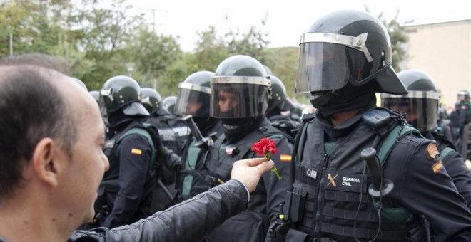 Un hombre ofrece un clavel a un agente de la Guardia Civil en el centro de votación de Sant Julià de Ramis (Girona) donde inicialmente tenía previsto votar el presidente de la Generalitat, Carles Puigdemont, en el referéndum independentista del 1-O./ EFE