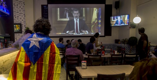 Varias personas miran el discurso del rey Felipe VI en un bar en Barcelona, al final de la jornada de paro general en protesta por la actuación policial durante el referéndum del 1-O. EFE/Quique García