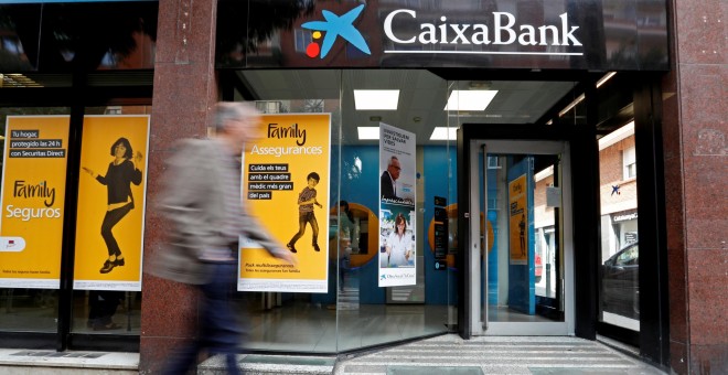Un hombre pasa junto a una sucursal de Caixabank en Barcelona. REUTERS/Yves Herman