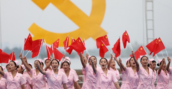 Enfermeras agitan pequeñas banderas nacionales chinas durante un acto previo al XIX Congreso Nacional del Partido Comunista Chino en Huaibei./REUTERS